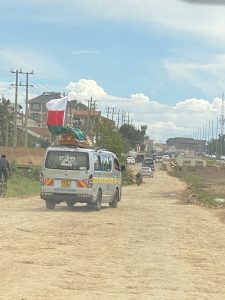 A coffin being carried on top of a van as part of a funeral procession.